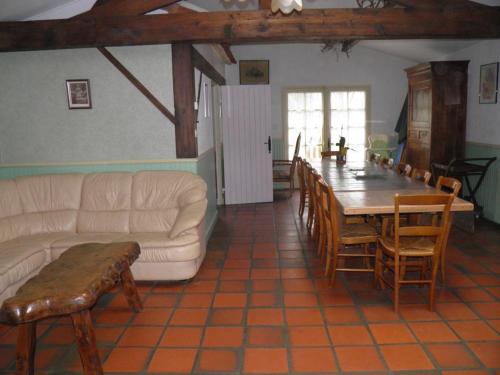 un salon avec un canapé, une table et des chaises dans l'établissement Gîte de caractère avec étang privé, jardin clos et cheminée, parfait pour les familles - FR-1-426-121, à Payré-sur-Vendée