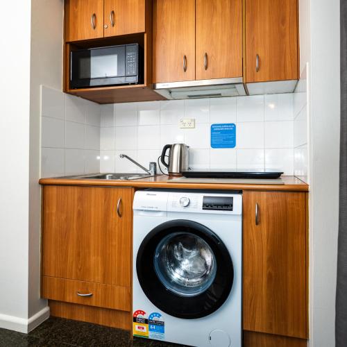 a washing machine in a kitchen with a microwave at 1 Bd Hotel Style Apartment Parramatta in Sydney