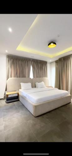 a large white bed in a bedroom with curtains at 3bedroom maisonette Banana, Ikoyi in Ikoyi