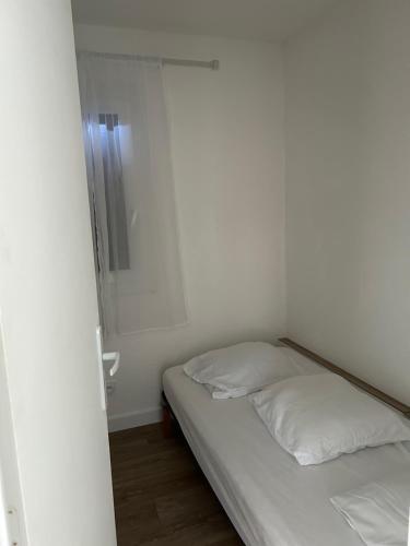 Cette petite chambre blanche comprend un lit et un miroir. dans l'établissement T1 bis résidence les coraux, à Canet