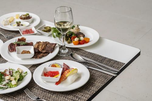 a table with plates of food and a glass of wine at Best Western Premier Gangnam Hotel in Seoul