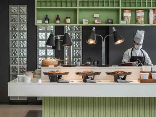 a chef in a kitchen with plates of food at Best Western Premier Gangnam Hotel in Seoul