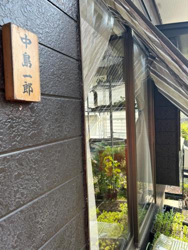 a window with a sign on the side of a building at なかじま宿 in Uenomachi