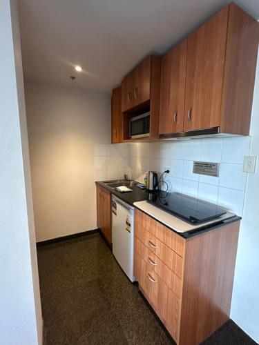 a small kitchen with wooden cabinets and a white refrigerator at 1 Bdr Hotel Style unit in parramatta - Free Parking in Sydney
