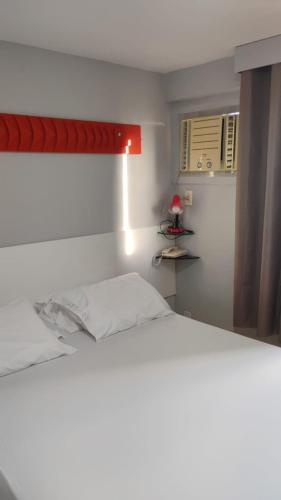 a bedroom with a white bed and a window at Boa Viagem Flat BVF 777 in Recife