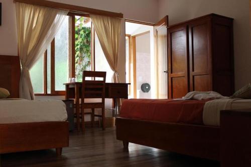 a bedroom with two beds and a desk and a window at Luz de Luna Escalante in San José
