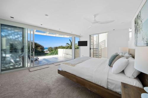 una camera da letto con un letto grande e un balcone di Absolute Beachfront Marcoola - Private Pool - Private Spa Bath - Games a Marcoola