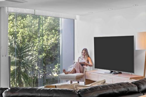 a woman sitting in a chair in front of a tv at Absolute Beachfront Marcoola - Private Pool - Private Spa Bath - Games in Marcoola