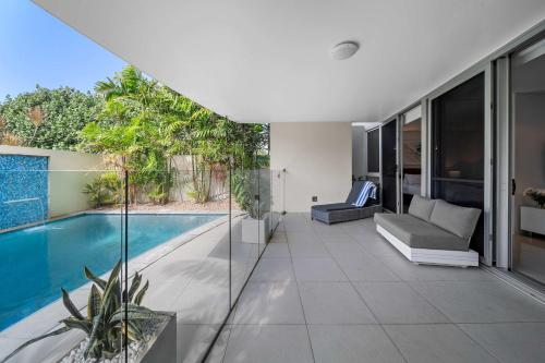 an indoor patio with a swimming pool and a house at Absolute Beachfront Marcoola - Private Pool - Private Spa Bath - Games in Marcoola