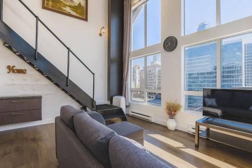 a living room with a couch and a tv at Trendy Downtown Loft Apartment - King Bed! in Vancouver