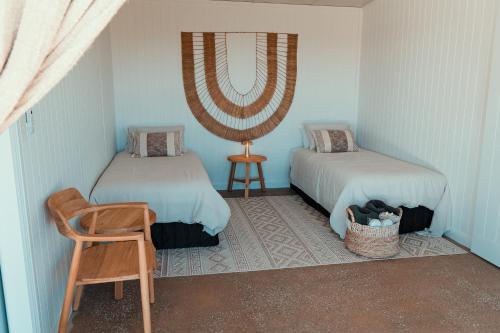 a room with two beds and a chair and a table at Glenayr Farm in Windeyer