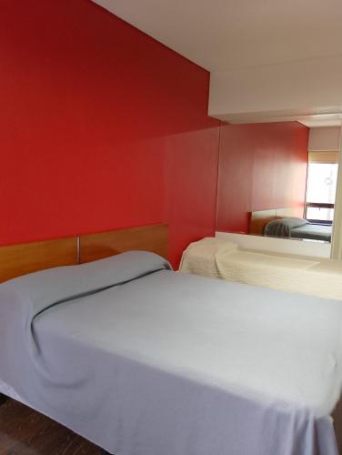two beds in a room with a red wall at Apart Rilax in Buenos Aires