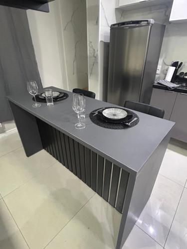 a table with two wine glasses and a plate on it at Studio Home 64 Luxo in Mogi das Cruzes