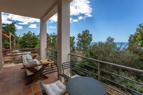 a patio with a table and chairs on a balcony at Hillside View, House 1 in Stoupa