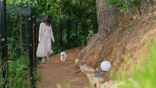 a woman walking a dog through a fence at Gyeongju Forest 258 Pet-friendly Pool Villa in Gyeongju
