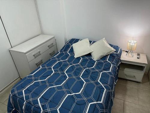 a bedroom with a bed with a blue and white comforter at Nueva Córdoba Ejecutivo in Cordoba