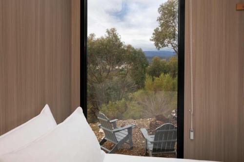 a bedroom with a view of a bed and chairs at Binbeal by Tiny Away in Steels Creek