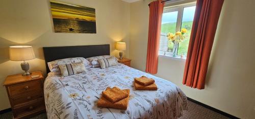 a bedroom with a bed with two pillows and a window at Ash Cottage in Stranraer