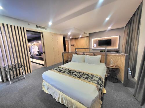 a hotel room with a large bed and a television at Roxy Hotel & Apartments in Kuching