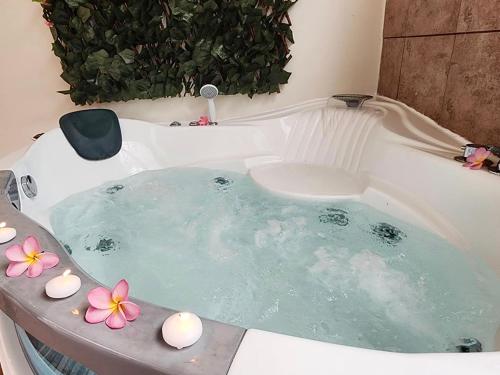 a jacuzzi tub with flowers and candles in it at Blue Horizon - Le Fare Ra'i - Jacuzzi - Garden in Mahaena