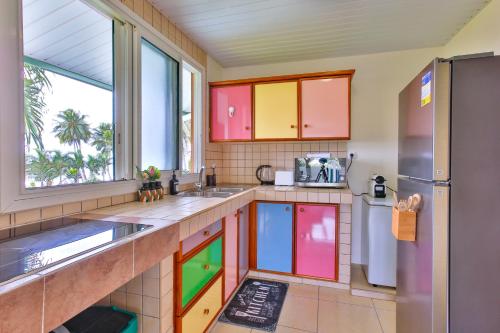 a kitchen with colorful cabinets and a refrigerator at Blue Horizon - Le Fare Ra'i - Jacuzzi - Garden in Mahaena