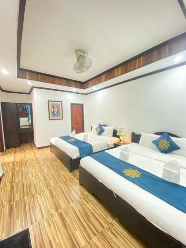 two beds in a hotel room with wooden floors at Singharat Boutique House in Luang Prabang