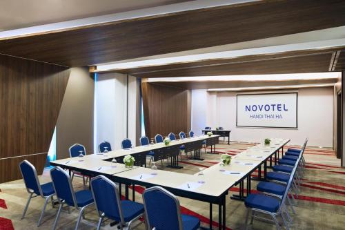 a conference room with a long table and blue chairs at Novotel Hanoi Thai Ha in Hanoi