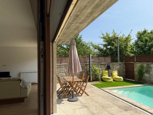 a patio with a table and an umbrella next to a swimming pool at Casa da Fonte - Gerês in Terras de Bouro