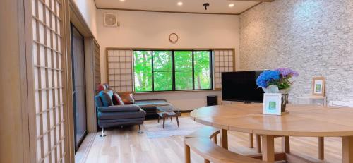 a living room with a table and a tv at TigerHouse in Nasu