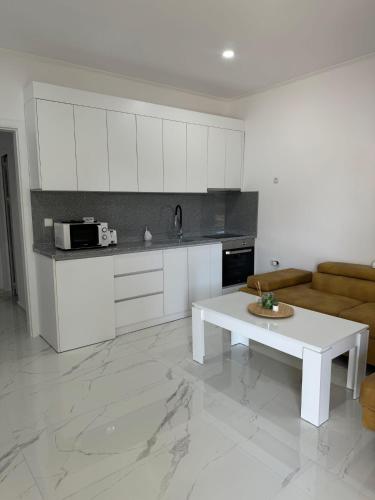 a white kitchen with a table and a couch at Pami in Néa Péramos