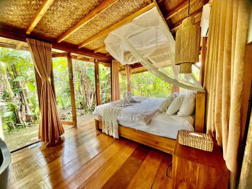 a bedroom with a bed with a mosquito net at Joglo Valley Villa by Rare Angon Ubud in Ubud