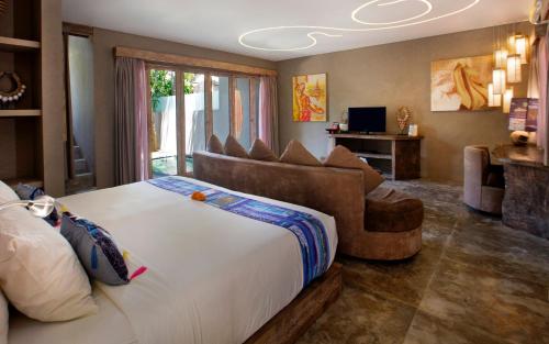 a bedroom with a large bed and a couch at Blue Karma Dijiwa Seminyak in Seminyak