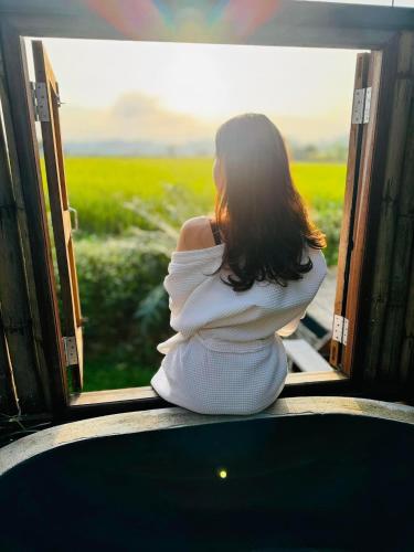 a woman sitting on a train looking out the window at DeeTorJai FarmStay Nan ดีต่อใจ ฟาร์มสเตย์ น่าน โดยเจ้าของ in Ban Klang