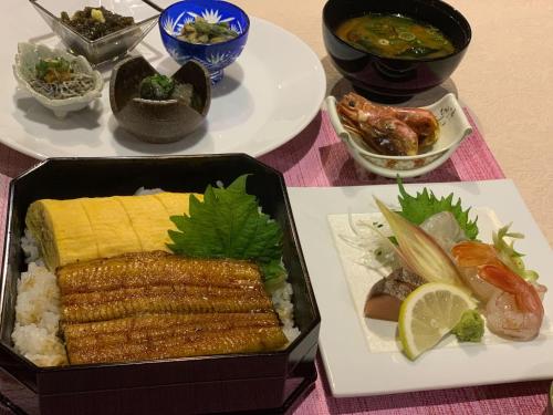a table topped with plates of food including rice and vegetables at Tabist Nanki Shirahama Ryokan Mantei in Shirahama
