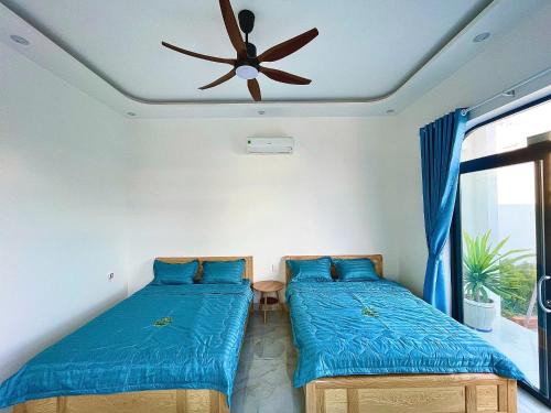 two beds in a room with a ceiling fan at Phú Quý MYNO Homestay in Cu Lao Thu