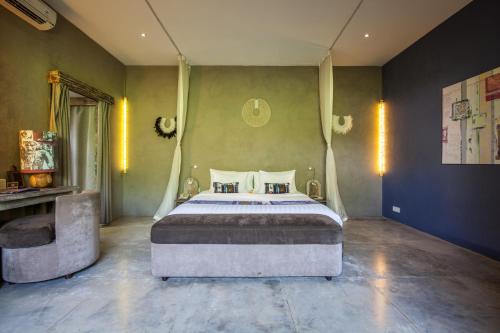 a bedroom with a large bed and a chair at Blue Karma Dijiwa Seminyak in Seminyak