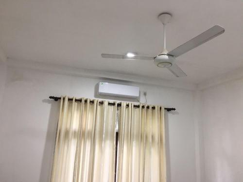 a ceiling fan and a window with a curtain at Bosadi Hotel katunayake in Katunayake