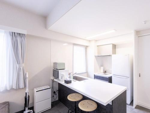 a kitchen with a white counter and two stools at MARSOL CS Beach hotel in Chigasaki