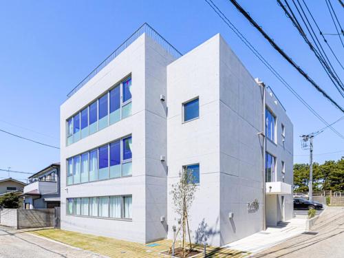 a white building with blue windows on a street at MARSOL CS Beach hotel in Chigasaki
