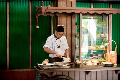 a man in a kitchen preparing food on a table at Garrya Tongsai Bay Samui in Choeng Mon Beach