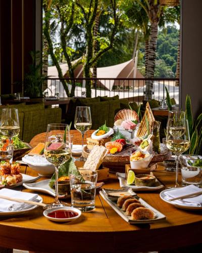 a wooden table with food and glasses of wine at Anantara Layan Phuket Resort in Layan Beach
