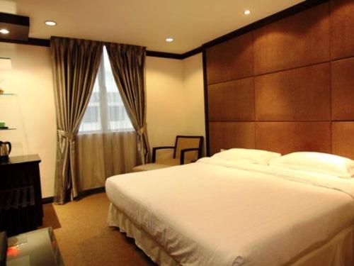 um quarto com uma grande cama branca e uma janela em Country Hotel em Klang