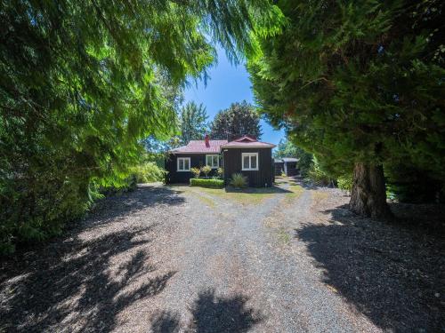 a house in the middle of a gravel driveway at Fiordland Hideaway - Te Anau Holiday Home in Te Anau