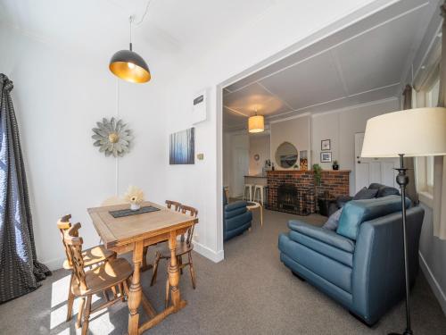 a living room with a table and blue chairs at Fiordland Hideaway - Te Anau Holiday Home in Te Anau