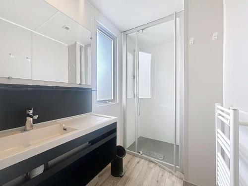 une salle de bain avec un lavabo et une douche en verre dans l'établissement Mobil-home Grand Confort 4 pers, 2 ch, piscine chauffée à 200m de la plage - FR-1-361A-65, à Jullouville