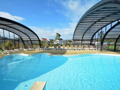 une grande piscine avec des chaises et un bâtiment dans l'établissement Mobil-home Grand Confort 4 pers, 2 ch, piscine chauffée à 200m de la plage - FR-1-361A-65, à Jullouville