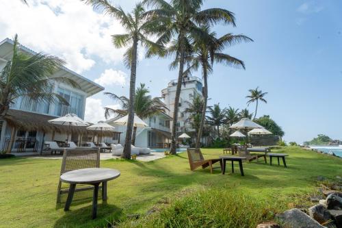 a resort with tables and chairs and palm trees at KUKI BEACH - Beachfront Villa in Ahangama in Ahangama