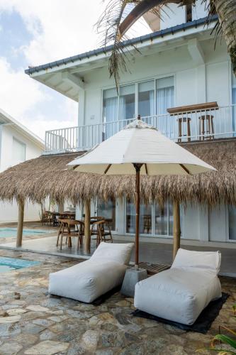 an umbrella and two pillows in front of a building at KUKI BEACH - Beachfront Villa in Ahangama in Ahangama