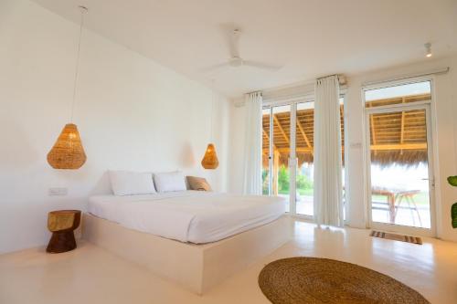 a white bedroom with a bed and a large window at KUKI BEACH - Beachfront Villa in Ahangama in Ahangama