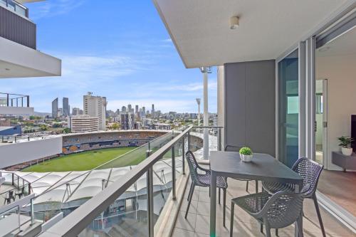 a balcony with a table and chairs and a view of a ballpark at Trafalgar Lane Apartments by CLLIX in Brisbane